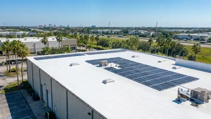 Aerial view of a newly installed white commercial flat roof featuring multiple solar panel arrays, skylights, and commercial HVAC units in Lakeland FL.