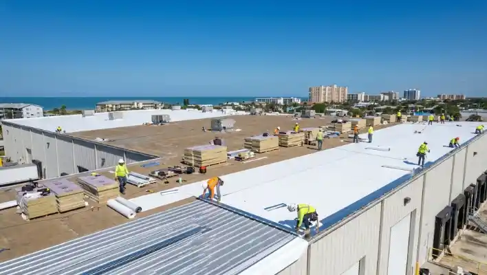 Commercial roofing contractors installing a white TPO flat roof replacement and high-efficiency insulation boards on a commercial building in Clearwater FL.
